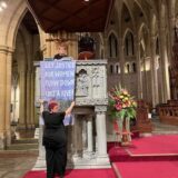 Rev Danni Clark and Rev Sandra Kjellgren hang a banner on the pulpit of St John's Cathedral in Brisbane.