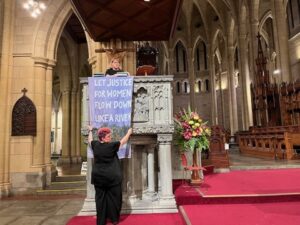 Rev Danni Clark and Rev Sandra Kjellgren hang a banner on the pulpit of St John's Cathedral in Brisbane.